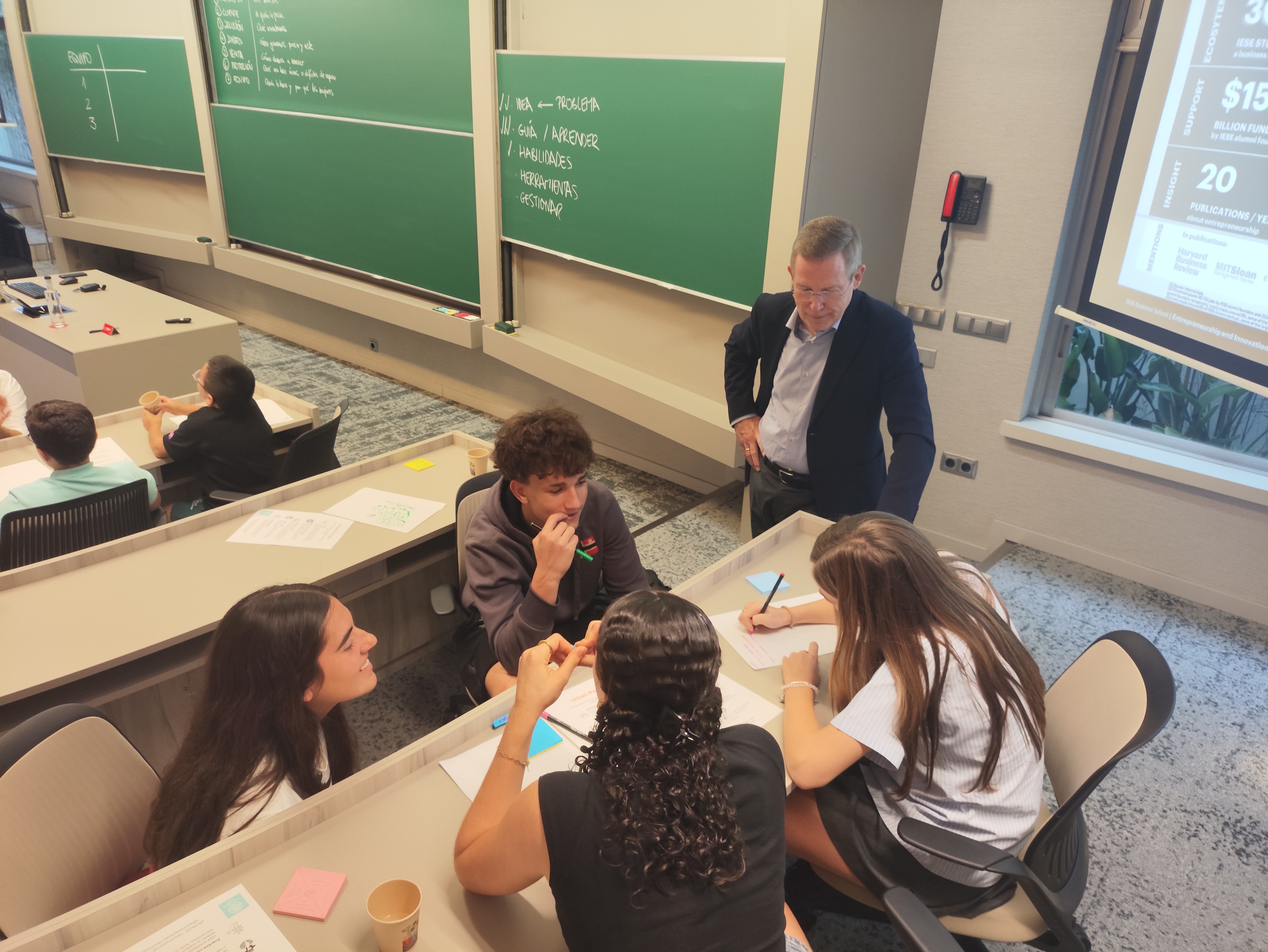 Estudiantes trabajando con profesor en aula de IESE Business School